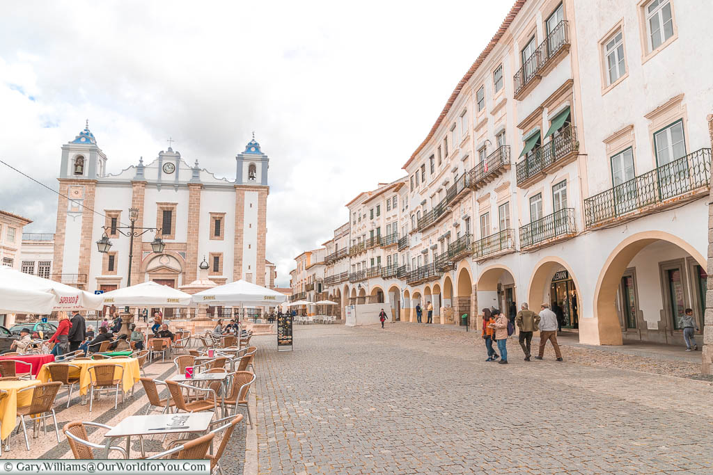 A street scene of the Praça do Giraldo in central Évora.  Tables and chairs lead the way to the Church of Saint Antão.