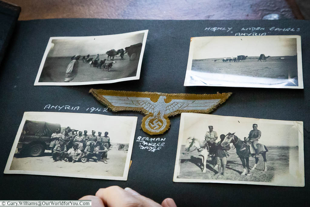 A page from the photo album, featuring four small photos, with a Nazi Panzer badge mounted in the centre.