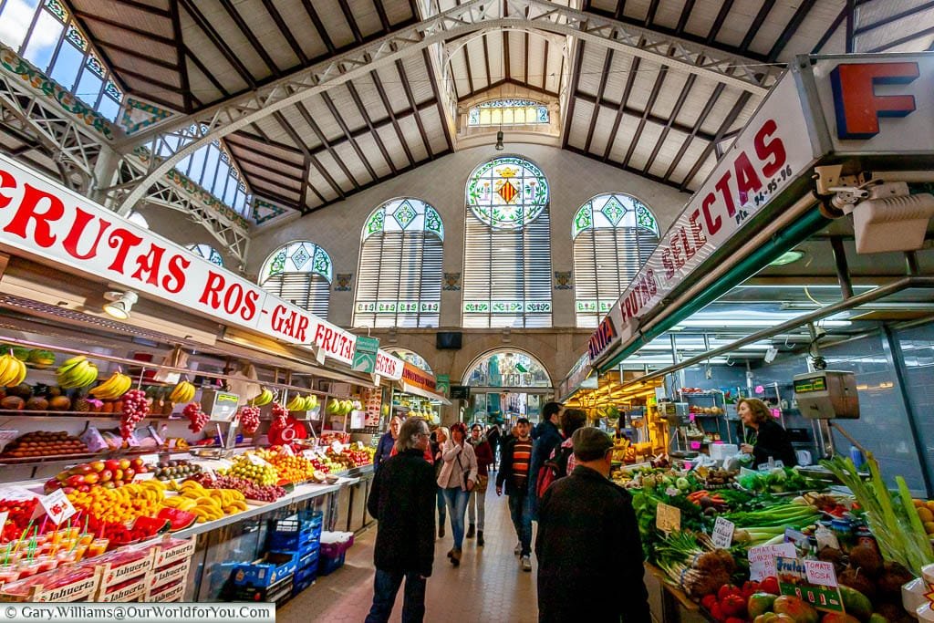 The main aisle of Mercado Central, Valencia, under its wrought-iron framework, looking toward the stained glass window.