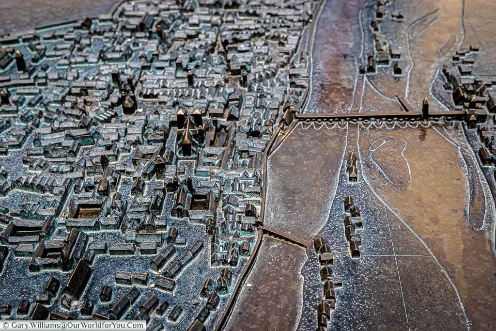 Looking down on a brass 3D map of the Old Town of Regensburg with the River Danube dominating the layout.