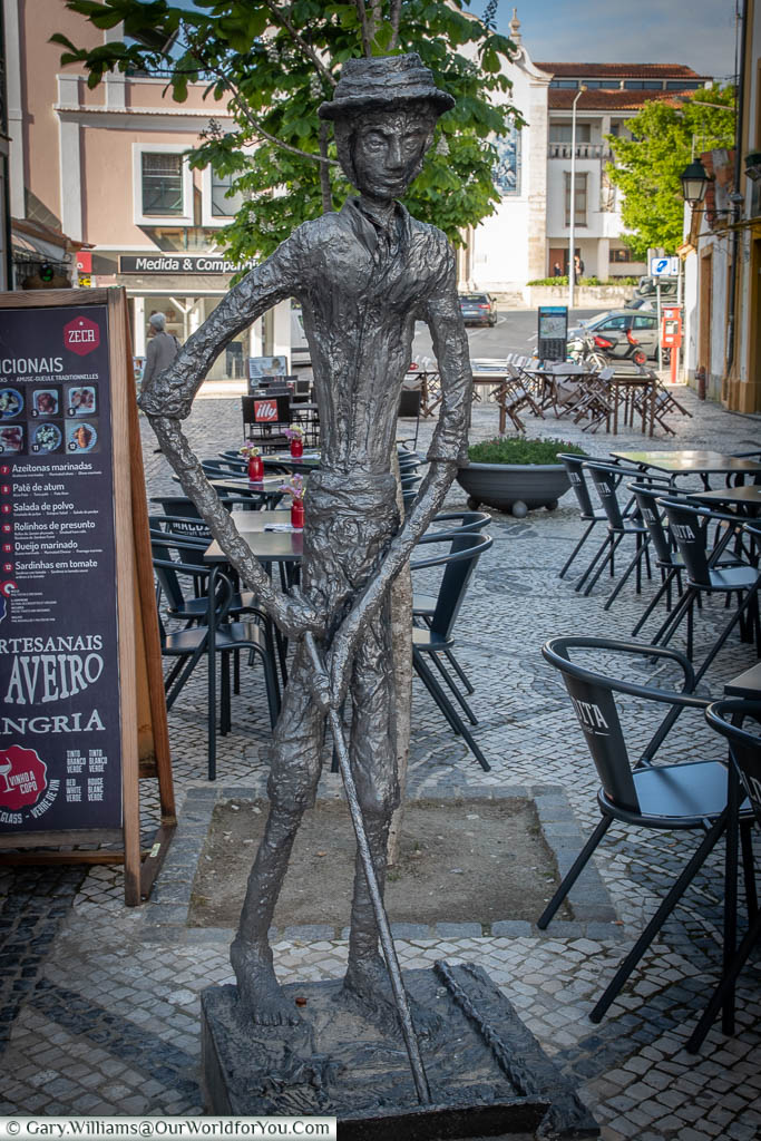 A bronze statue of a gaunt figure holding a salt panning rake in Aveiro's town centre.