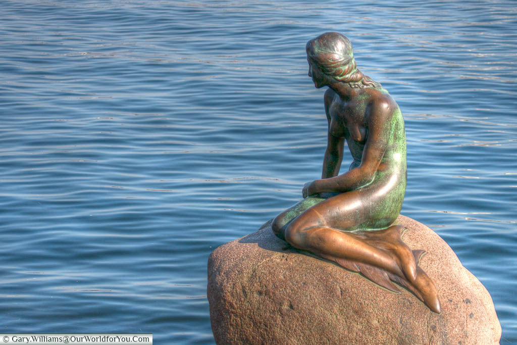 The bronze statue to Hans Christian Andersen's 'The Little Mermaid' perched on a rock by the waterside at the Langelinie promenade in Copenhagen, Denmark