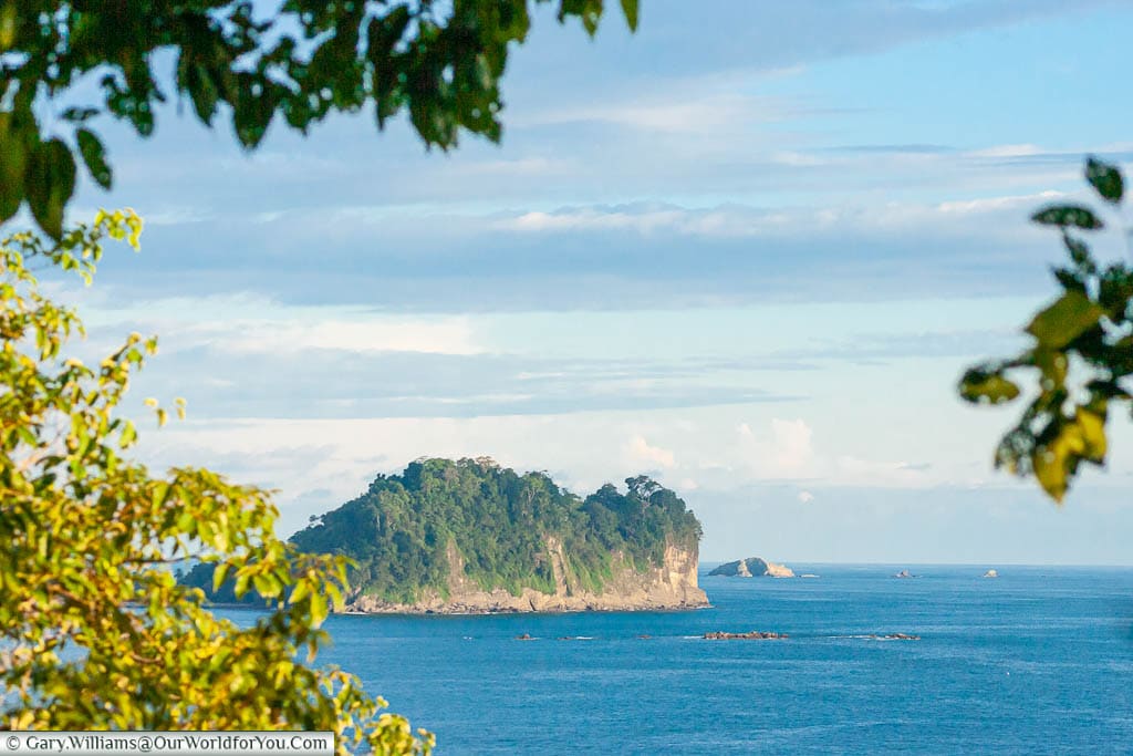 A view through the gardens of the Hotel Parador to a lush green island in the Pacific Ocean, Manuel Antonio, Costa Rica