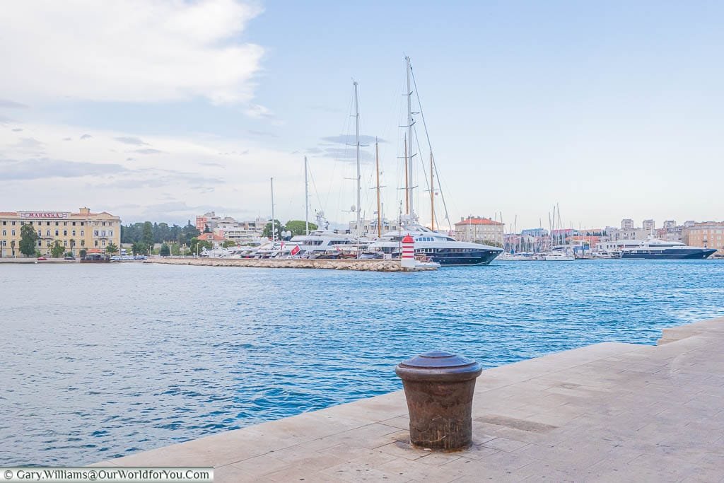 Standing on the marina side, with expensive, superyachts and tall sailing ships moored up, overlooking the ancient city of Zadar, Croatia