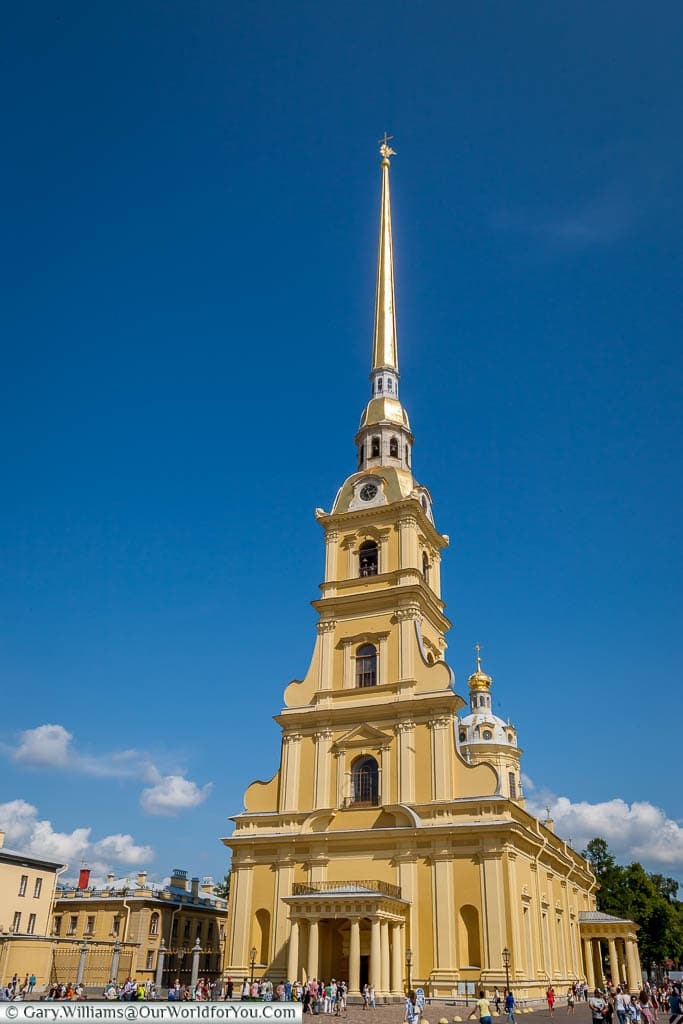 The mustard yellow Saints Peter and Paul Cathedral, topped with a narrow gold spire in Saint Petersburg, Russia