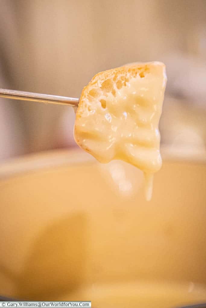 A cube of bread, on a skewer, dipped in melted cheese from our fondue.