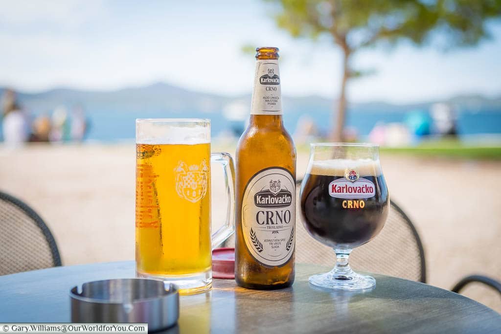 A dark Karlovačko Crno and a golden Karlovačko pilsner by the coastline in Zadar, Croatia