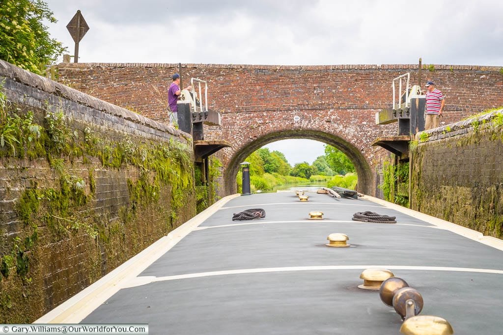 A father & son opening the lock gates on the Kennet & Avon canal to allow a narrowboat to pass through.