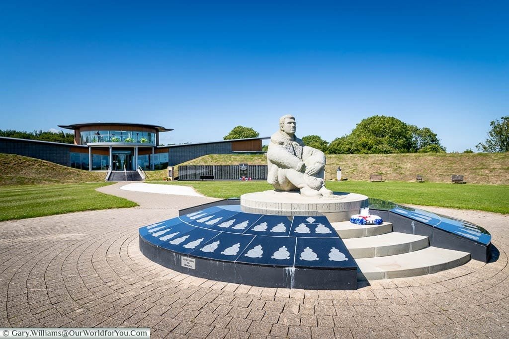A statue of a pilot, seated on the ground, at the centre of the Battle of Britain Memorial at Capel-le-Ferne.