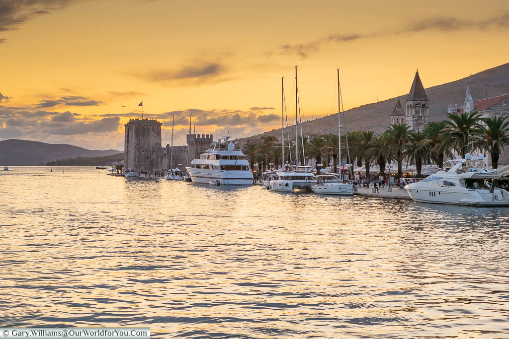 Boats moored up next to the riva in Zadar under the orange sky of dusk