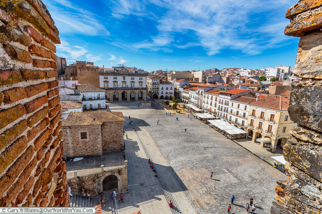 A view over the empty Plaza Mayor from between the stone defences of the Bujaco Tower in Cáceres, Spain