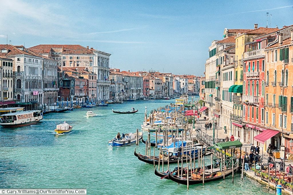 A view from the Rialto Bridge along the busy Grand Canal of Venice, with colourful buildings lining either side