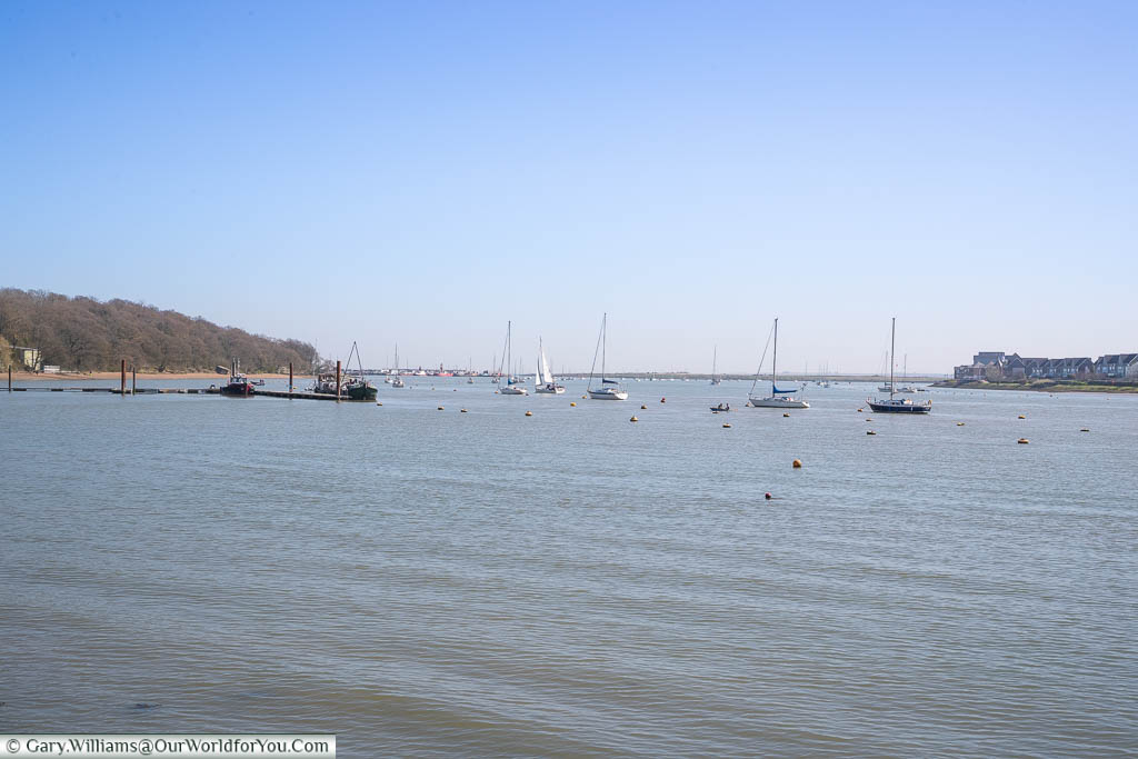 View along the River Medway from Lower Upnor as it stretches out towards the Thames, with numerous small sailing boast moored up in the centre of the channel