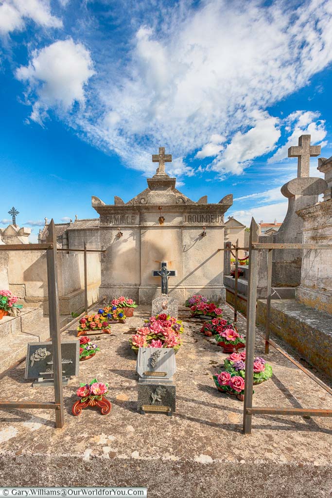 A large stone grave plot, decorated with porcelain floral tributes in the cemetery of Saint-Rémy-de-Provence, France