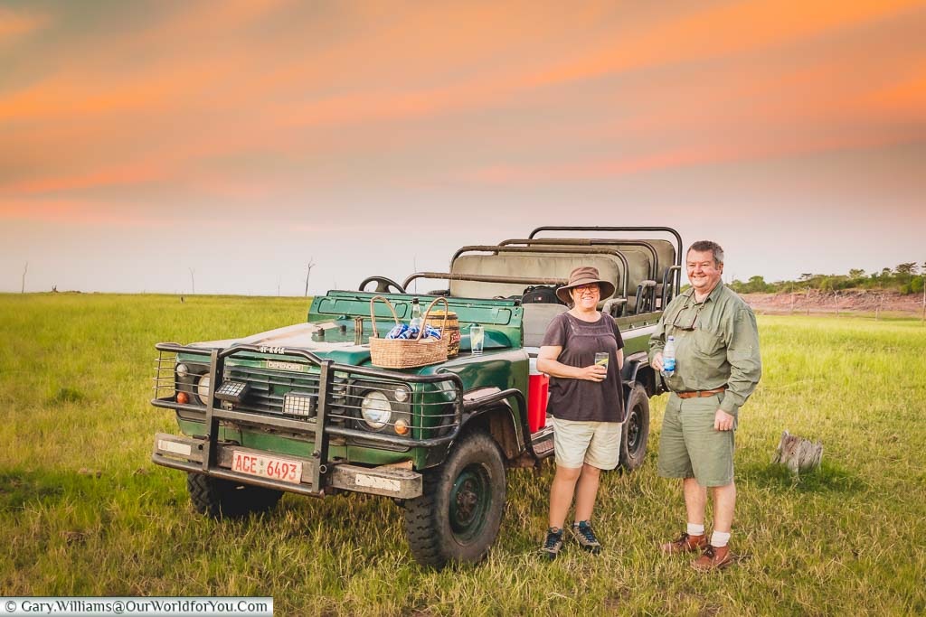 Janis and our guide Mark chat next to our trusty Landrover during a break on our evening safari drive at Rhino Safari Camp next to Lake Kariba in Zimbabwe