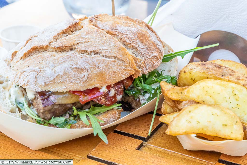 A prego, a Portuguese steak sandwich, served with a side order of potato wedges, at a table outside a cafe in Guimarães