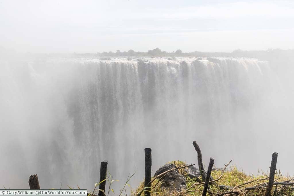 Standing at a viewpoint overlooking the main section of Victoria Falls. At high water season the amount of water cascading over the falls creates a heavy mist that hangs in the air.