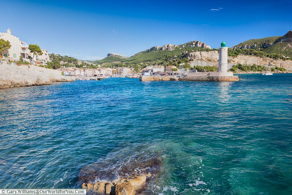 The entrance to the harbour at Cassis protected by a lighthouse, with the provencal town, in the background.