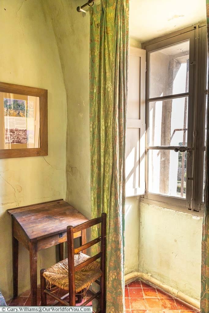 Light flowing into a stark room in the Monastery of Saint-Paul de Mausole with just a small table and chair in the corner.