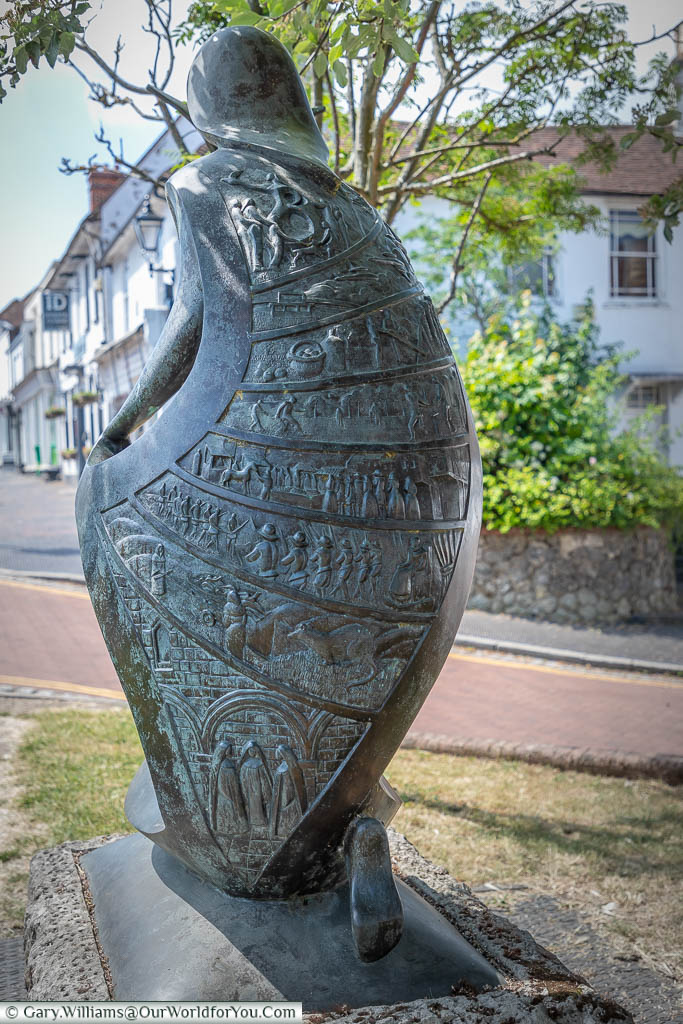The rear of the 'Hope' sculpture where the cloak covering the statue is inlaid with 8 panels depicting scene throughout West Malling's history