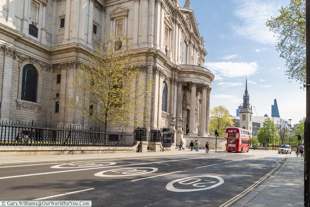 A traditional red bus travelling through the deserted streets of London next to St Paul's Cathedral