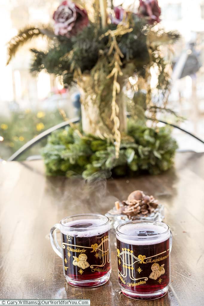 Two glasses of Glühwein served in decorated glass mugs at a table in the bandstand in Düsseldorf