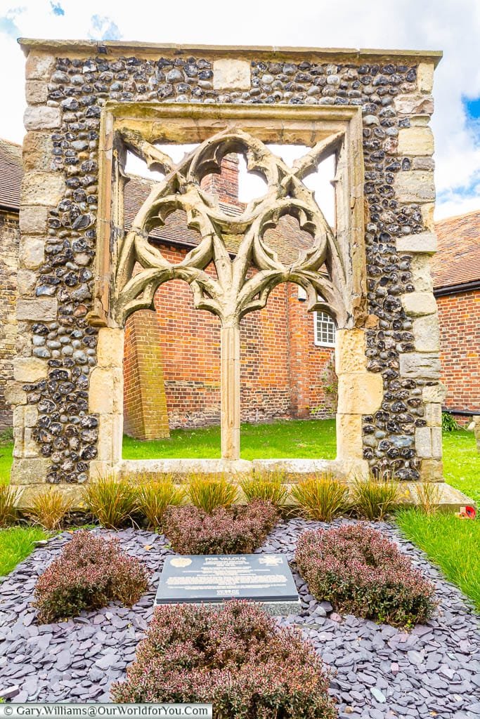 The stone memorial to Victoria Cross recipient Augustus Charles Newman set in the ground in front a recovered gothic church window