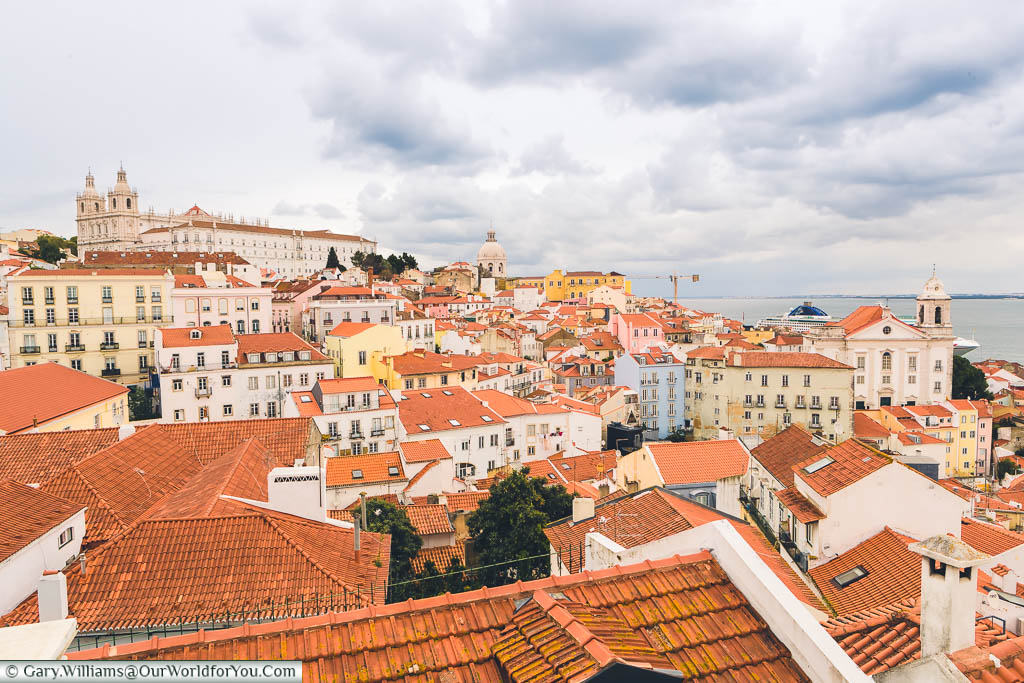 Looking east from the viewpoint of Portas Do Sol over the terracotta tiles roofs of Lisbon with the Church of São Vicente de Fora on the hillside, and the National Pantheon in the distance.