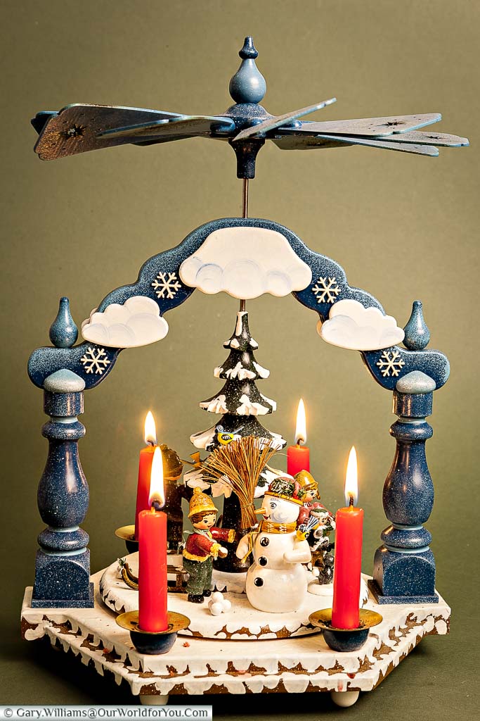 Our Käthe Wohlfahrt Christmas carousel, depicting a snowy festive scene, with four lit red candles, under the fan blades.