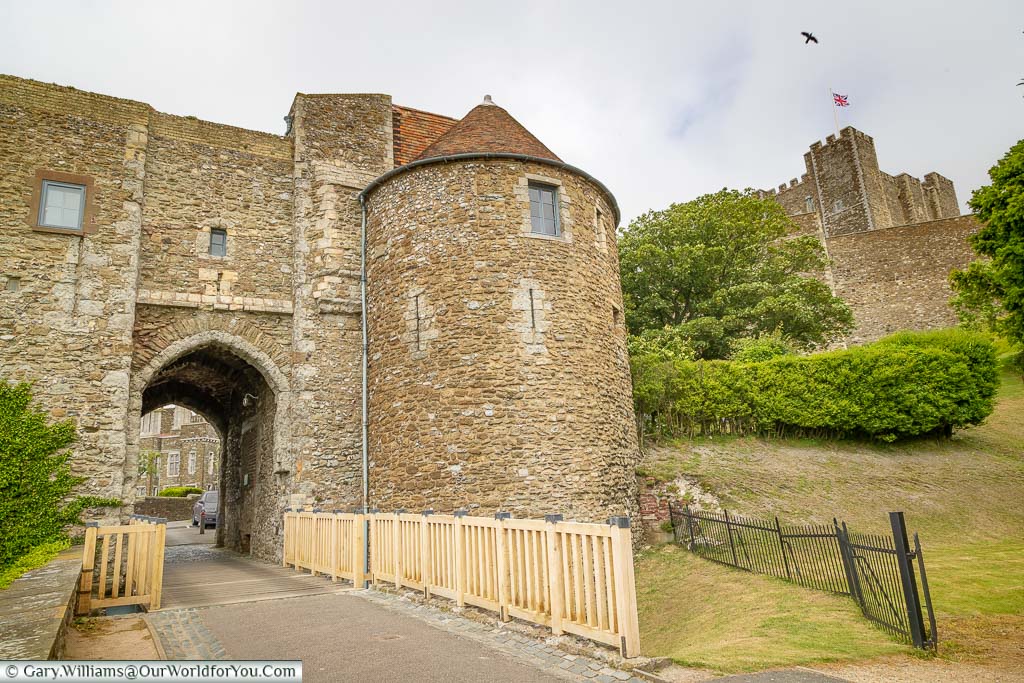 A stone gatehouse at Dover Castle with the Keep high on the hillside
