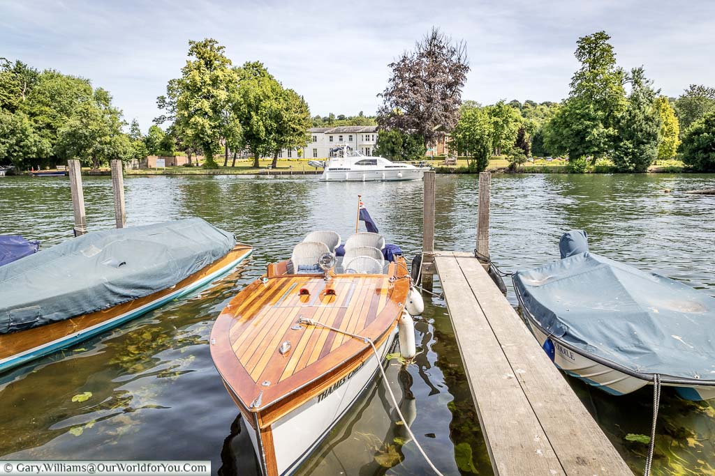 A stylish wooden panelled motor launch moored up on the River Thames opposite the home to the Henley Royal Regatta.