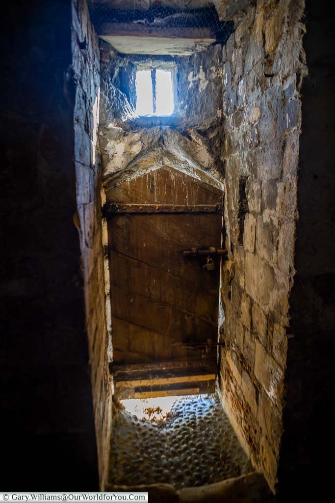 Light seeping into the interior of the basement of Deal Castle past an ancient wooden door.