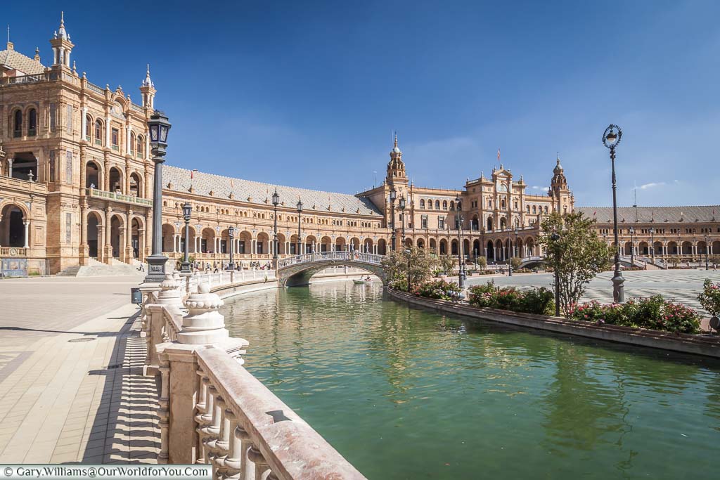 A view of the walkway next to the canal in the Plaza de España, next to the ornate buildings that surround it.