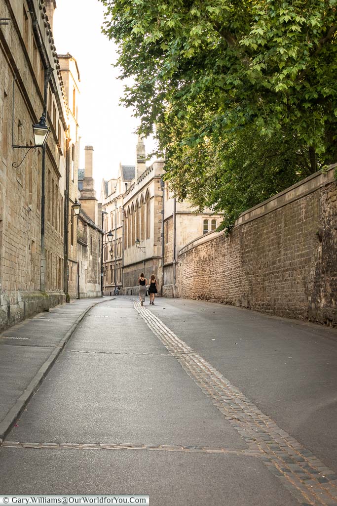 A couple of young ladies strolling towards the sunlight in Brasenose Lane.