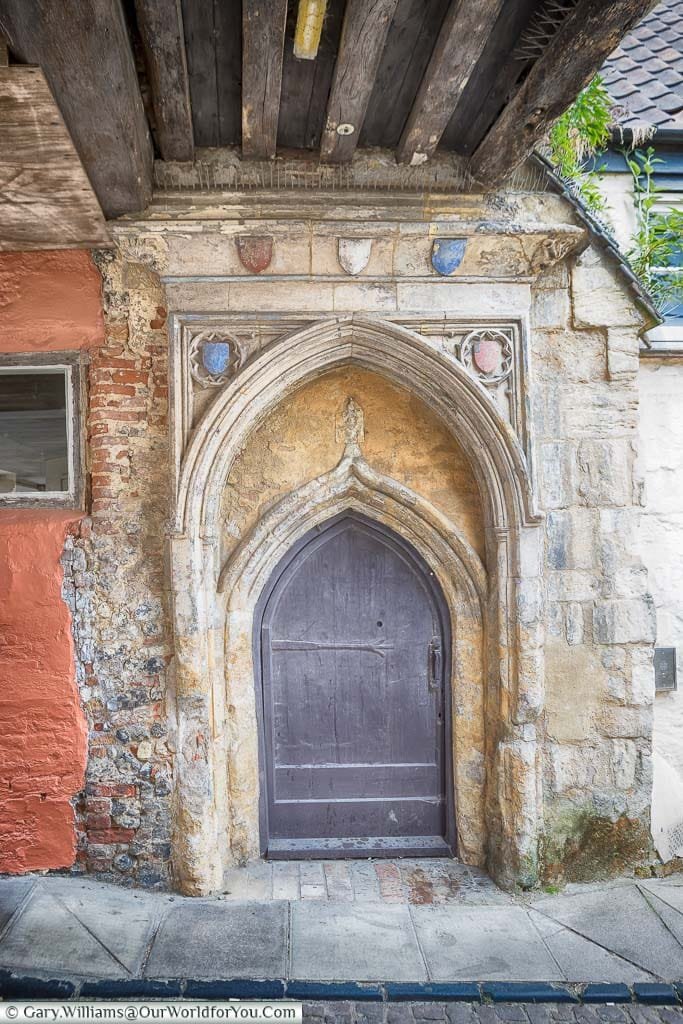 A small medieval wooded door in a stone surround that leads into the Dragon Hall in Norwich