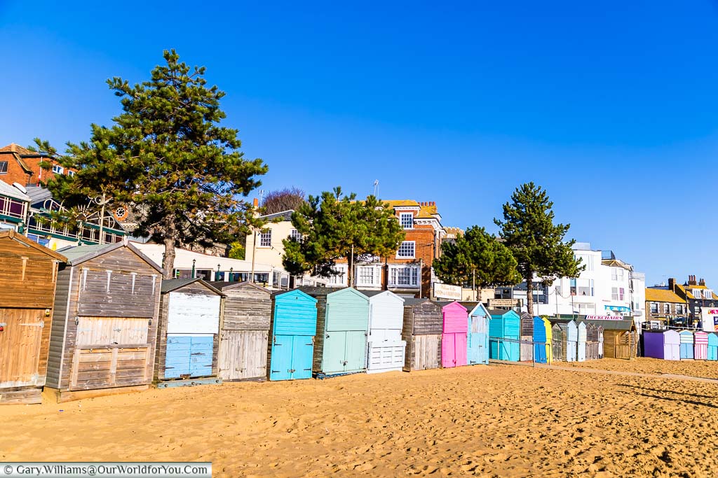Some brightly coloured beach huts mingle between plain wooden huts on the golden sands of Broadstairs’ beach