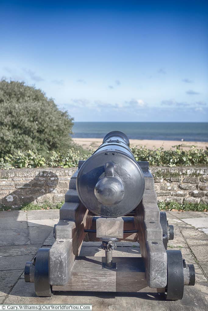 A cast-iron cannon on its wooden carriage, pointing out over the defensive wall of Walmer Castle to the English Channel beyond