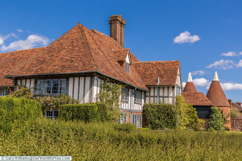 A typical Tudor era cloth hall half-timbered house alongside another symbol of Kent, the white topped oast houses in the village of Rolvenden, Kent