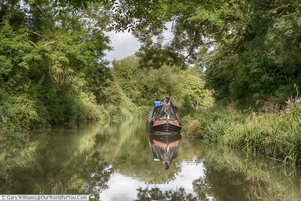 A narrow beam canal boat that is clearly somebodies home is moored up in an idyllic lush green scene as we chug along the Kennet and Avon Canal