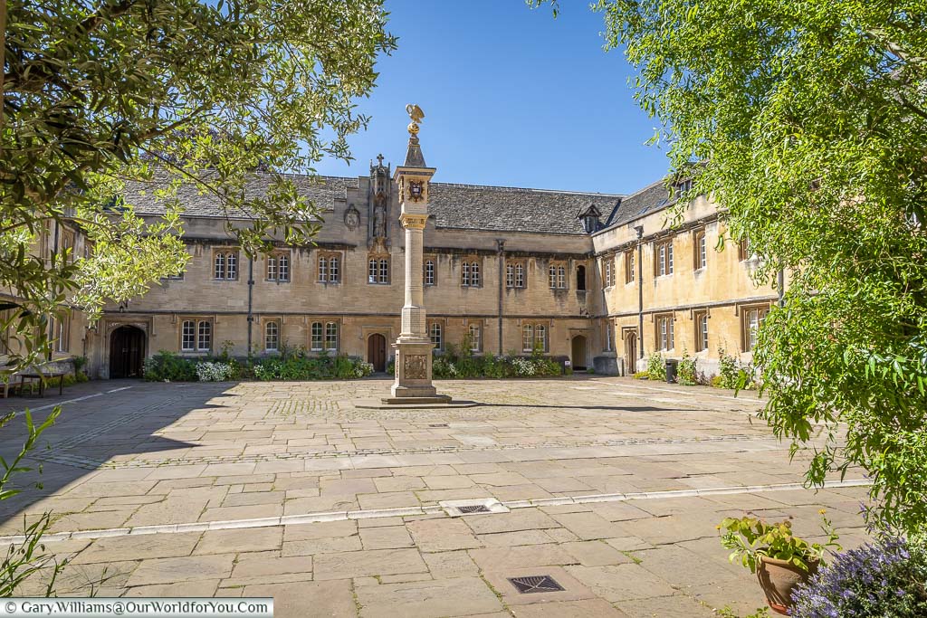 A stone square dominated by the Pelican Sundial at the entrance of Corpus Christi College, Oxford
