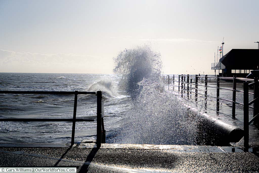 Spray being thrown up as waves crash against Broadstairs sea wall on a bright sunny winter's day