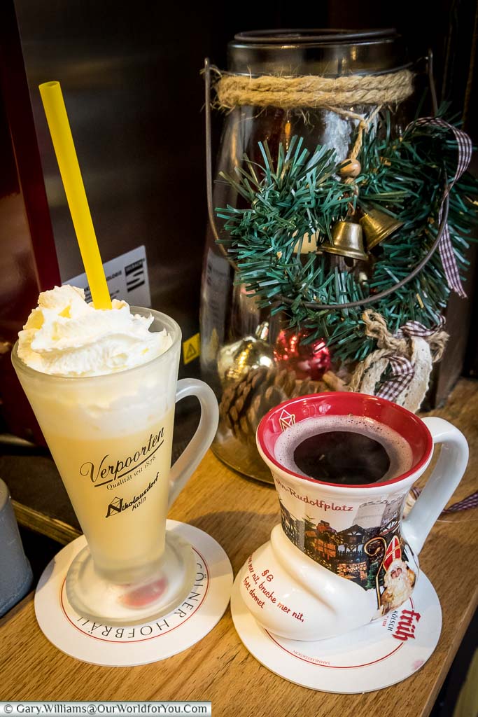 A boot-shaped mug of Gluhwein and a warming eggnog, topped with whipped cream in a frosted glass