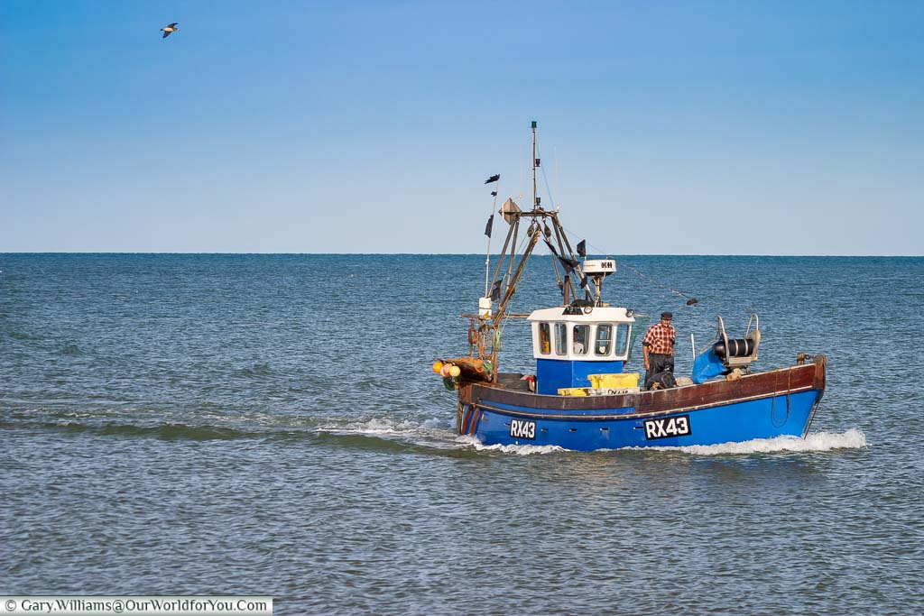 A small fishing trawler returning to the shore of Dungeness with its catch of the day
