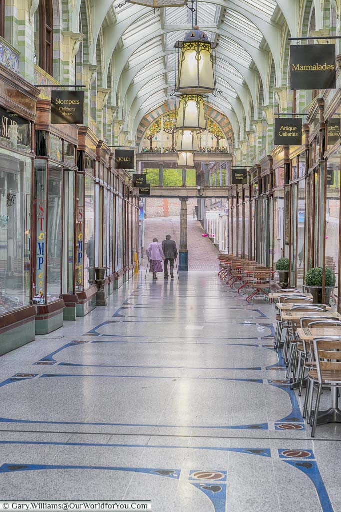 Inside the Art Deco Royal Arcade in Norwich, with its pretty mosaic tiled floor and lanterns suspended from an iron and glass vaulted ceiling.