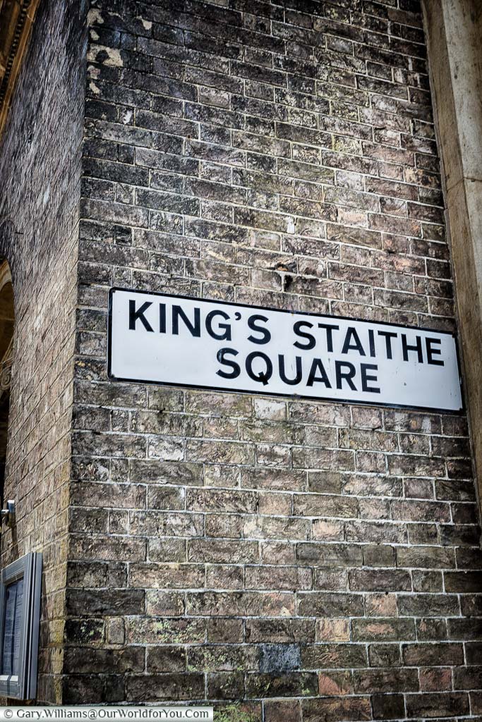 A traditional Street sign for 'King's Staithe Square' on the corner of an old brick-built building in King's Lynn, Norfolk
