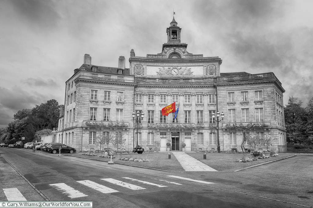 A partially desaturated image of the town hall, or L'Hôtel de Ville, of Alençon.  The only colour in the shot is the red & yellow of the Normandy flag and the blue and yellow of the E.U. flag.