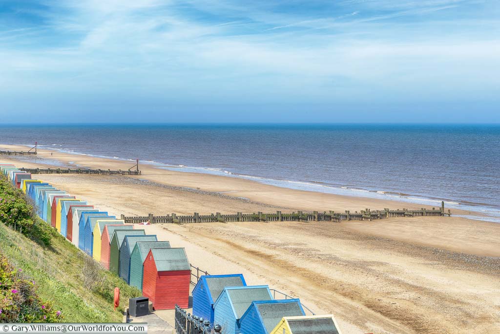 A line of colourful beach huts line the edge of the golden sands at Mundesley Beach on the North Norfolk Coastline
