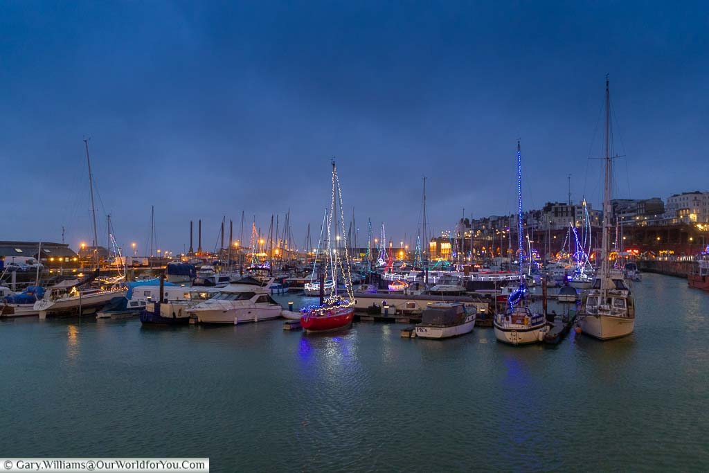 Ramsgate’s harbour at night in the run up to Christmas with the masts of the boats decorated with twinkling lights.