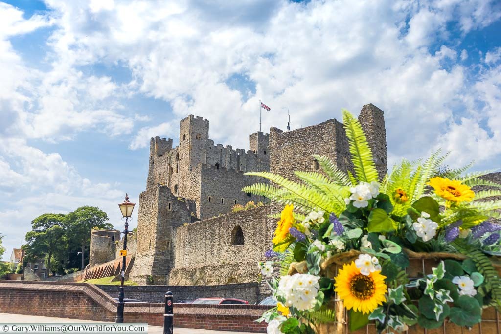 Looking up at Rochester Castle from the bottom of Boley Hill from behind a flower display