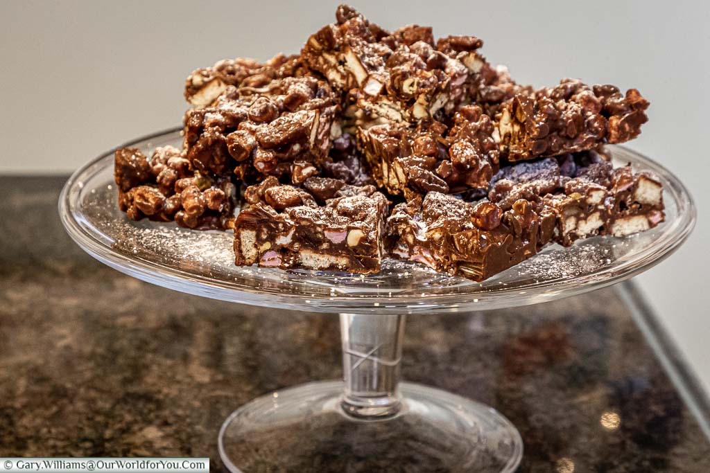 A glass cake stand loaded with homemade Rocky Road squares
